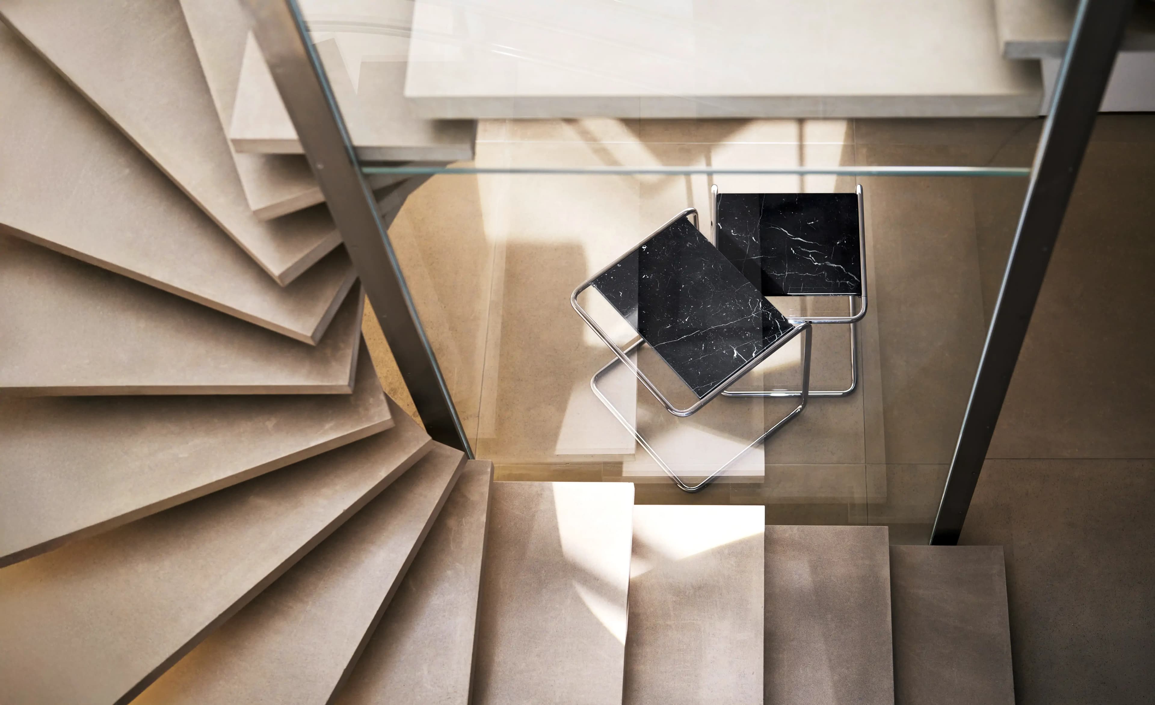 Editorial image for JS . THONET: B 97 nesting side tables with black marble tops beside a spiral staircase.