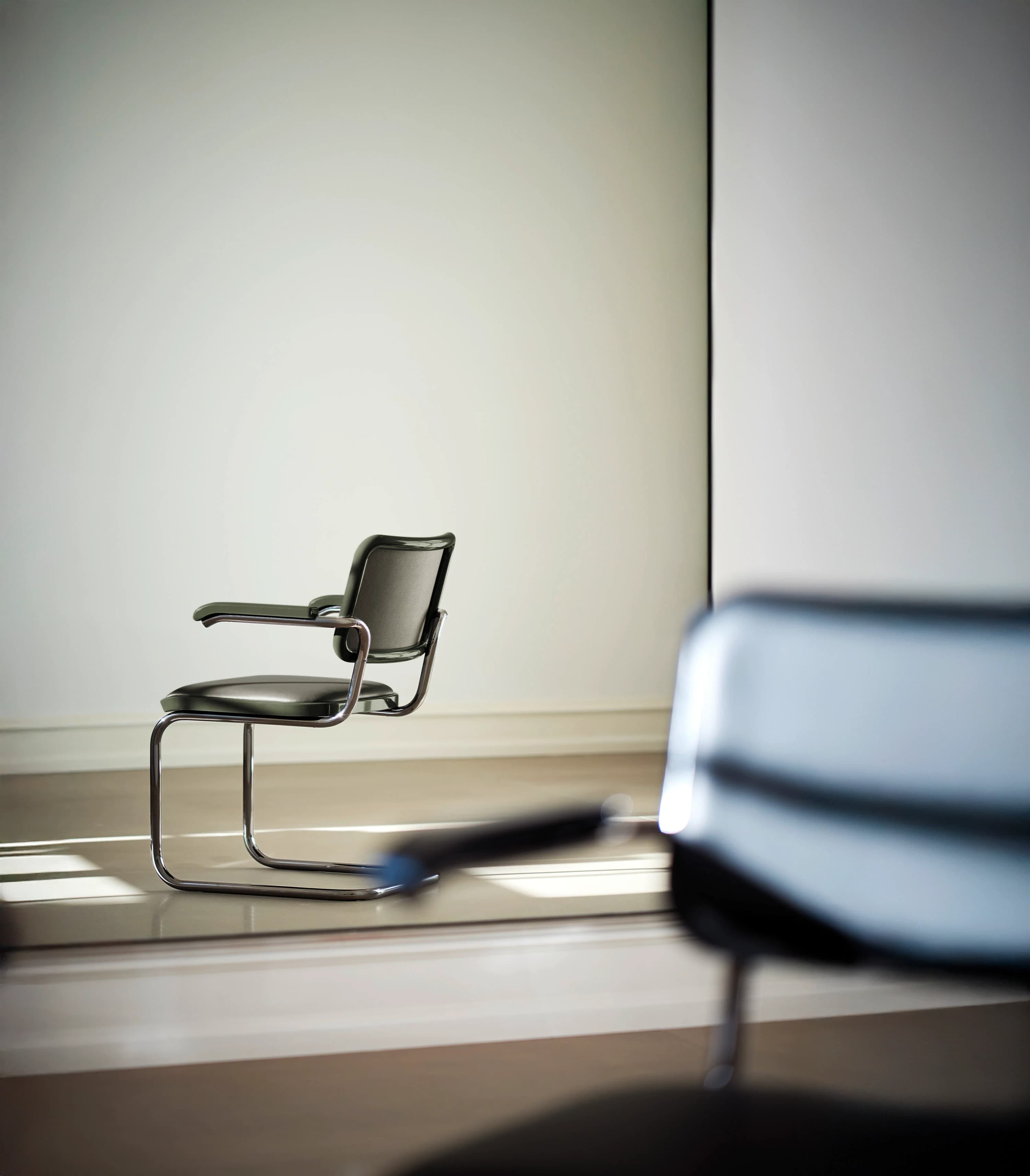 Editorial image for JS . THONET: Leather-upholstered cantilever chair S 64 in front of a mirror, with the chair reflected in the background.