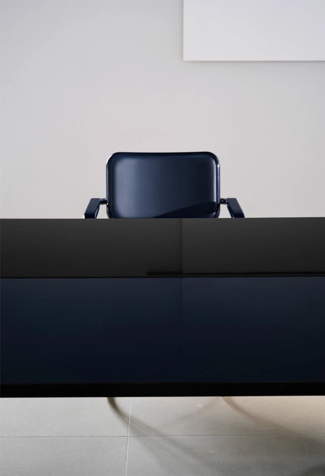 Editorial image for JS . THONET: S 64 SERIOUS chair backrest behind a glossy dining table in a minimalist room.