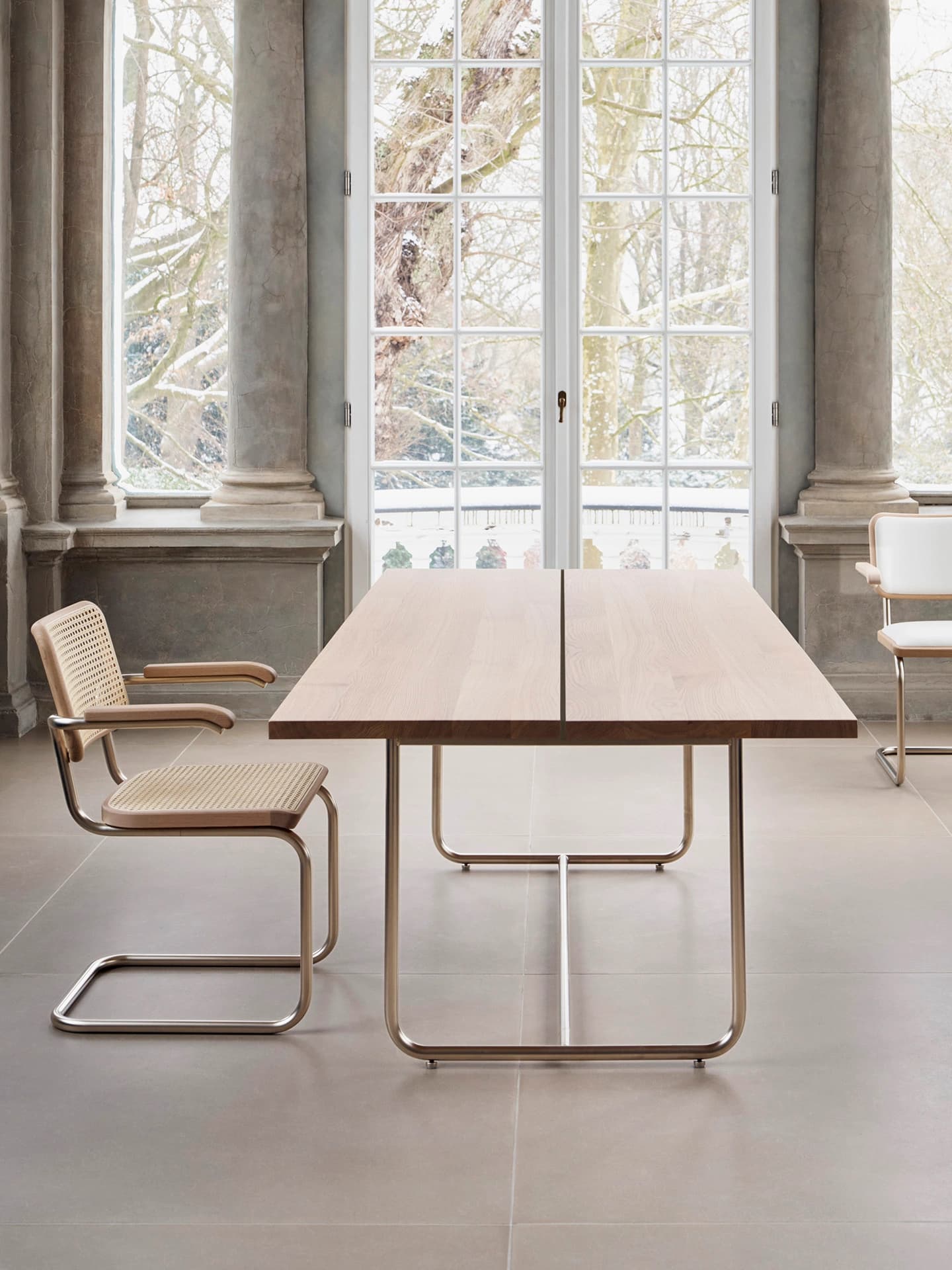 Editorial image for JS . THONET: S 64 V NORDIC 04 cantilever chair with cane seat and backrest beside a wooden table in a bright room.